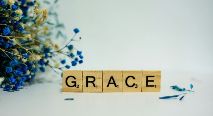 Scrabble tiles spelling Grace with flowers.